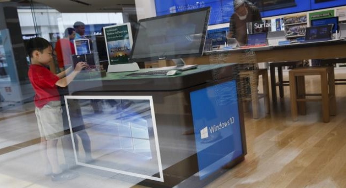 A child stands at a computer display stand for the Windows 10 operating system at the Microsoft store at Roosevelt Field in Garden City